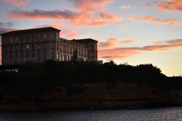 Gün batımında sahilde büyük bir bina.