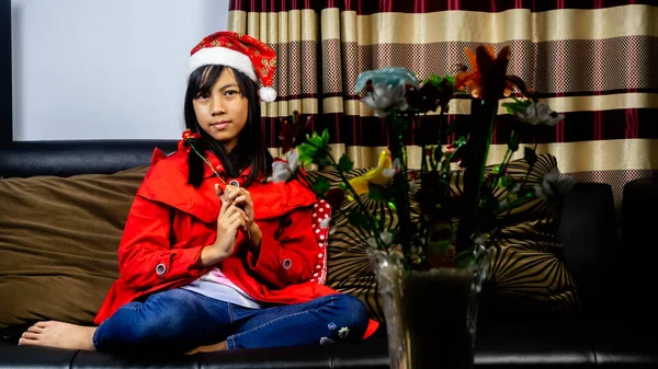 小女孩穿着圣诞老人的衣服坐在一张黑色的沙发上 — 图库照片