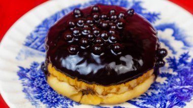 Kırmızı arka planda bir tabakta çikolatalı çörek.