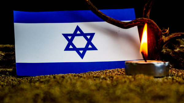 Israeli flag and burning candles in front of it, Holocaust memory day