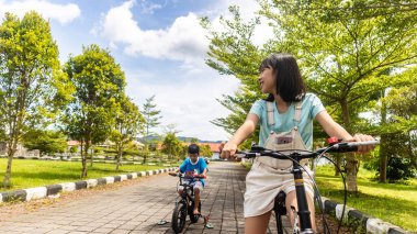 Çocuklar güzel bir bahçede bisiklet oynuyorlar.