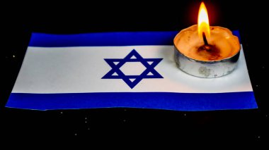 İsrail bayrağı ve üzerinde yanan mumlar. Soykırım anıları günü.