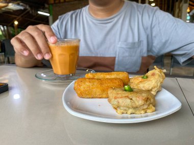 Geleneksel Endonezya yemeğinin tadını çıkaran bir kişi, bir krupuk ile bir kase soto ayam, tofu ve kroket gibi kızarmış atıştırmalıklar ve bir bardak çay sunar..