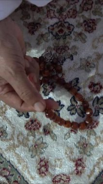 Dua etmek için kolye tutan Asyalı Müslüman bir kadının (tasbih) yakın çekimi. Ruhsal öğretim ve meditasyon. İslami kavramlar.