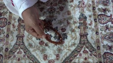 Dua etmek için kolye tutan Asyalı Müslüman bir kadının (tasbih) yakın çekimi. Ruhsal öğretim ve meditasyon. İslami kavramlar.
