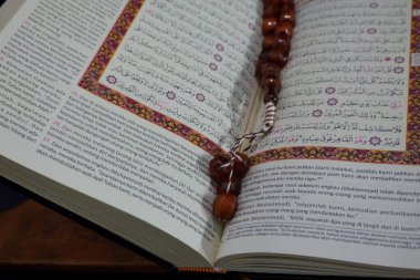 Banda Aceh, Endonezya - 10 Aralık 2024: Üzerinde dua boncukları ve karmaşık desenlerle süslenmiş Arapça kaligrafi içeren kutsal bir Kur 'an. Huzurlu bir ortamda ruhanilik ve bağlılık.
