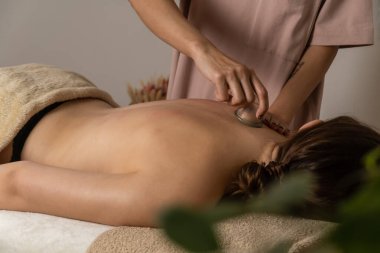 Spa salonundaki masaj terapisti, hastasının sırtına elektrikli süpürge ile masaj yapıyor, yakın çekim için. Sağlıklı bir vücut ve yaşam tarzı kavramı