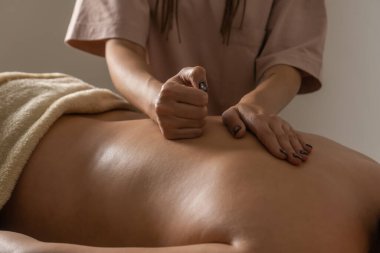 Masörün elleri, salonda rahat bir atmosferde bir kadına sırt masajı yapıyor. Sağlıklı yaşam tarzı ve vücut bakımı kavramı.