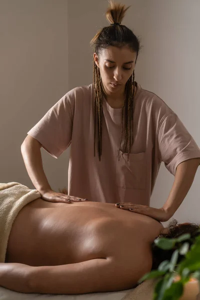 Female masseur gives a relaxing back massage to a woman in a spa salon. Concept of health, self-care. Vertical photo