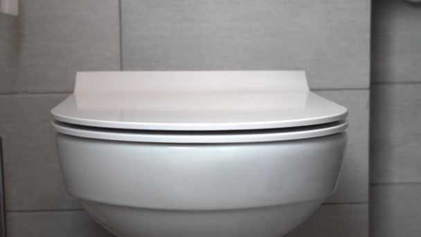 人間の手はトイレのボウルの保護蓋を開きます 人のトイレに行きたいと白いぶら下げトイレボウルのリフトの蓋 近代的な配管とバスルーム — ストック動画
