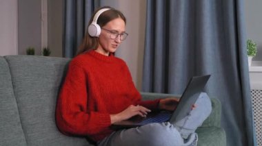 Kulaklıklı mutlu genç kız Webinar dinliyor konferans videosu aracılığıyla iletişim kuruyor ve uygulamalı kahkaha çalışmasında öğretmenlik dersi alıyor. Laptopa evde bakın.