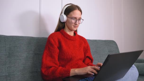 Νεαρή Γυναίκα Στα Ακουστικά Διεξάγει Κλήσεις Συνέδριο Στο Φορητό Υπολογιστή — Αρχείο Βίντεο