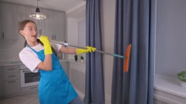 Beyaz beyaz beyaz beyaz kadın komedyen önlüklü ve beyaz tişörtlü paspas ile dans ederken tatillerde evindeki mutfak odasını temizliyor, şarkı söylüyor ve tuhaf hareket ediyor. Temizlik şirketi..