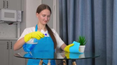 Profesyonel ekipmanlı temizlik personeli özel evi temizliyor, hijyen yapıyor. Genç hizmetçi, üniformalı kız eli temizliği temizlemek için sprey kullanıyor, mavi bez kullanıyor, temizliyor, temizliyor. yavaş çekim