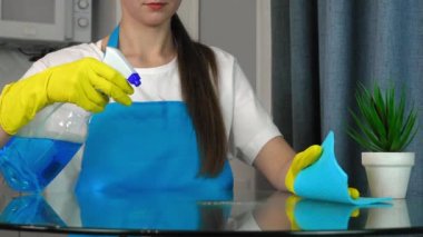 Genç beyaz kadın masayı paçavrayla temizliyor. Mutfak temizlikçisinin güzel temizliği. Ev işleri ve ev işleri konsepti. Ekip ve deneyimli işçiler. Reklamcılık. yavaş çekim.