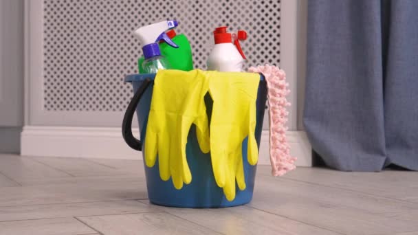 女性が掃除に従事しているアパートやキッチン 背景にブラシ ボトル スポンジ ラグと黄色のゴム手袋 バケツで製品を洗浄します 清掃会社広告 — ストック動画