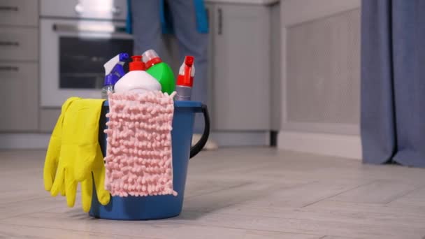 女性が掃除に従事しているアパートやキッチン 背景にブラシ ボトル スポンジ ラグと黄色のゴム手袋 バケツで製品を洗浄します 清掃会社広告 — ストック動画