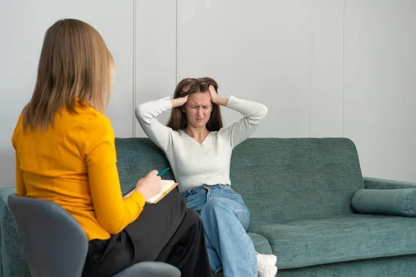 在心理学家的预约中 一位年轻的女性正坐在沙发上 低着头 体验着负面的情绪 心理社会学概念 — 图库照片