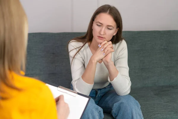 Woman psychologist talks and helps girl. recording important studies in tablet, view from back or behind. psychology, mental health concept of people. Reception with psychotherapist.