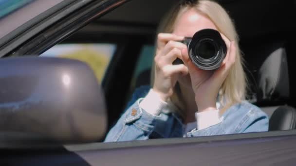カメラを持つ女性は車の中に座って プロのカメラ 私立探偵やPaparazziスパイと写真を撮る ジャーナリストは同期を求め 有名人に従う — ストック動画