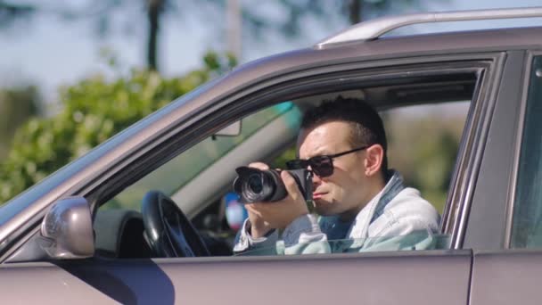 カメラを持つ男は車の中に座って プロのカメラで写真を撮る 私立探偵やPaparazziスパイ ジャーナリストは同期を求め 有名人に従う — ストック動画