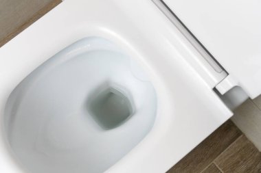 Modern tuvaletteki yeni beyaz seramik tuvaletin üst görüntüsü.