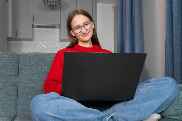 스웨터를 안경을 소파에 거실에서 노트북을 사용하고 재미있는 비디오를 언어를 배우고 — 스톡 사진