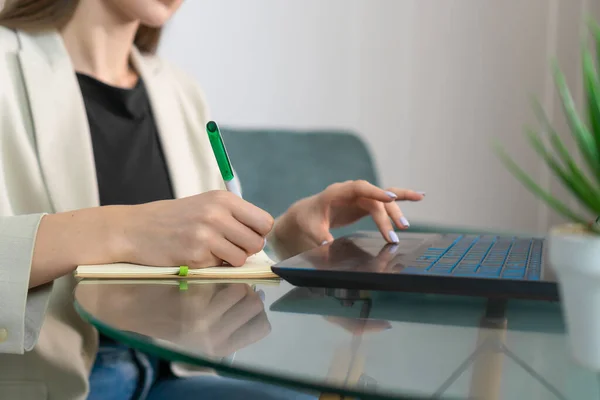 Zbliżenie Ręki Kobiety Robiącej Notatki Notatniku Podczas Pracy Nad Laptopem — Zdjęcie stockowe