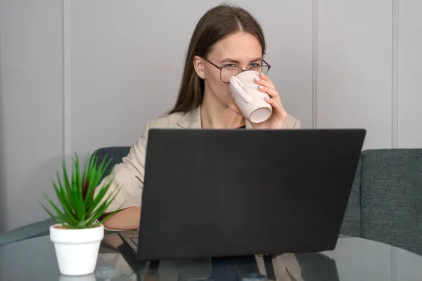 Piękna Młoda Kobieta Kurtce Szklanki Pije Kawę Pomocą Laptopa Siedząc — Zdjęcie stockowe
