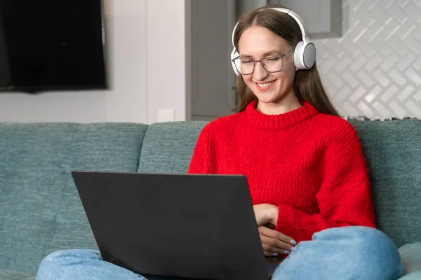 Young Woman Red Sweater Jeans White Headphones Surfing Net Couch — Stock Photo, Image