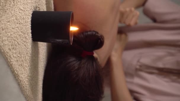 按摩师在温泉沙龙按摩女人的身体 美容美发概念 芬芳的烛光带着温暖和舒适的气氛在前景中燃烧 身体护理 美容美发 垂直视频 — 图库视频影像