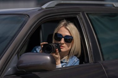 Paparazzi kadın ya da kız arabasında oturup ünlü birinin fotoğraflarını çekiyor. Arabada kamera olan bir casus. Özel dedektif ya da paparazzi gazeteci arabada oturuyor, kamerayla fotoğraf çekiyor..