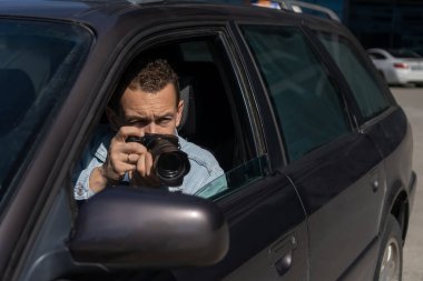 Gizli fotoğrafçılık. Paparazzi Concep Fotoğrafçısı profesyonel kamerasını kullanıyor. Araba vitrinindeki özel dedektif. Mobil muhabir. İş yerinde foto muhabiri. Dedektif ya da dedektif..