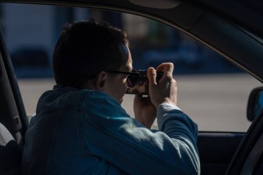 Gizli fotoğrafçılık. Paparazzi Concep Fotoğrafçısı profesyonel kamerasını kullanıyor. Araba vitrinindeki özel dedektif. Mobil muhabir. İş yerinde foto muhabiri. Dedektif ya da dedektif..