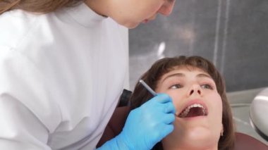 Diş hijyenisti, diş aletleriyle çalışıyor. Hastanın dişlerini kontrol ediyor. Diş kliniğinde diş tedavisi prosedürü. Tıbbi aletlerle dişlerin incelenmesi Kadın portresi,