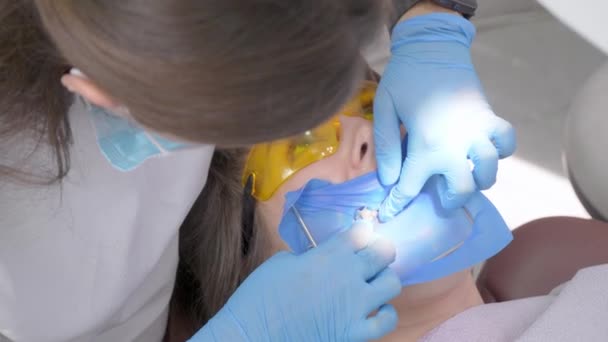 歯科医は運河やパルピティスの治療のために金属クリップでラテックススカーフを準備します 口腔内にはラテックス断熱布が設置されています 腐った虫歯の治療と回復 — ストック動画
