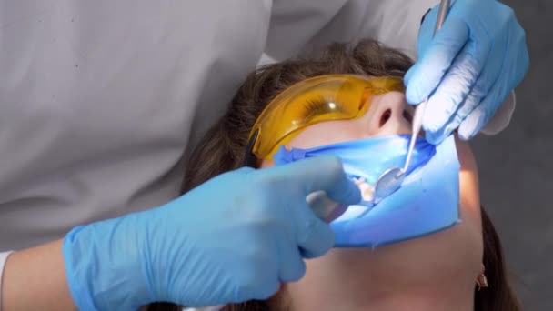 女牙医和女助手从牙齿上摘除牙结石 参观会前牙科诊所 女人坐在牙椅上 牙齿的钻孔及处理 — 图库视频影像