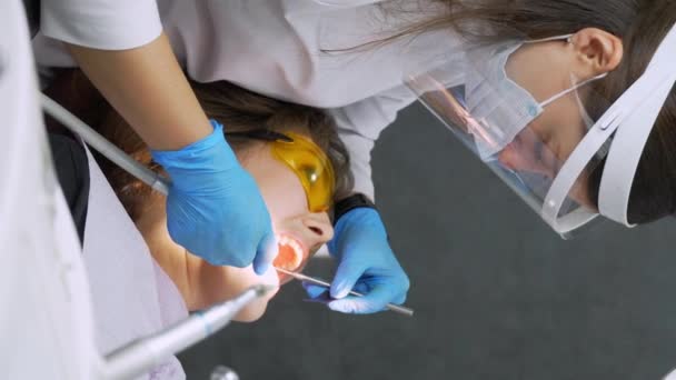 女牙医和女助手从牙齿上摘除牙结石 参观会前牙科诊所 女人坐在牙椅上 牙齿的钻削和处理 垂直视频 — 图库视频影像