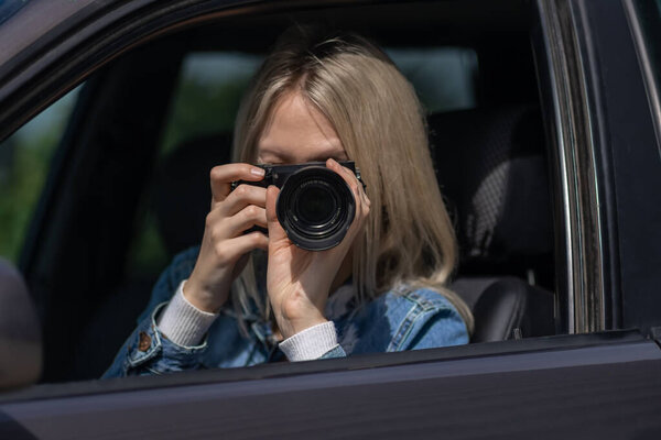 Hidden photographing. Paparazzi Concep Photographer uses his professional camera. Photographer girl in car window. Mobile reporter. Photojournalist at work. Detective or investigator.