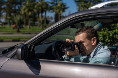 Paparazziler ya da güneş gözlüklü adamlar onun arabasında oturur ve ünlü birinin fotoğraflarını çeker. Arabada kamera olan bir casus. Özel dedektif ya da paparazzi gazeteci arabada oturuyor, kamerayla fotoğraf çekiyor..