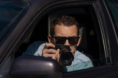 Gizli fotoğrafçılık. Paparazzi Concep Fotoğrafçısı profesyonel kamerasını kullanıyor. Araba vitrinindeki özel dedektif. Mobil muhabir. İş yerinde foto muhabiri. Dedektif ya da dedektif..