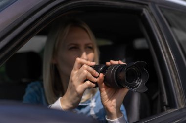 Gizli fotoğrafçılık. Paparazzi Concep Fotoğrafçısı profesyonel kamerasını kullanıyor. Araba vitrinindeki fotoğrafçı kız. Mobil muhabir. İş yerinde foto muhabiri. Dedektif ya da dedektif..