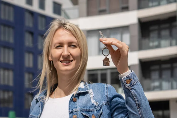 微笑的年轻女子手里拿着一把钥匙 站在一幢有公寓的新房子的后面 购买公寓 房地产的概念 — 图库照片