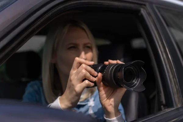 Hidden photographing. Paparazzi Concep Photographer uses his professional camera. Photographer girl in car window. Mobile reporter. Photojournalist at work. Detective or investigator.