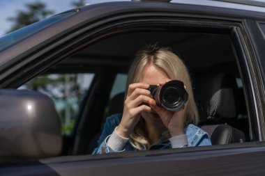 Paparazzi kadın ya da kız arabasında oturup ünlü birinin fotoğraflarını çekiyor. Arabada kamera olan bir casus. Özel dedektif ya da paparazzi gazeteci arabada oturuyor, kamerayla fotoğraf çekiyor..