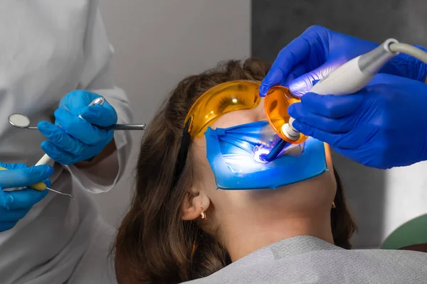 Dentysta Wypełnia Ząb Pacjenta Kompozycją Wypełnienia Asystent Świeci Lampą Ultrafioletową — Zdjęcie stockowe