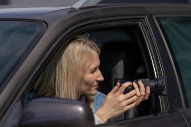 Paparazzi kadın ya da kız arabasında oturup ünlü birinin fotoğraflarını çekiyor. Arabada kamera olan bir casus. Özel dedektif ya da paparazzi gazeteci arabada oturuyor, kamerayla fotoğraf çekiyor..