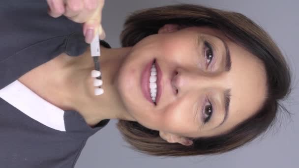 惠特化概念 牙科护理 植入物的供应商 在牙科诊所 美丽的白种人老年妇女笑得完美 选择了牙齿的色调 现代医学 垂直视频 — 图库视频影像