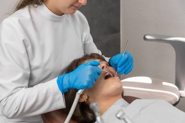 Dentysta Ochronnych Niebieskich Rękawiczkach Bada Zęby Młodej Kobiety Pomocą Sondy — Zdjęcie stockowe