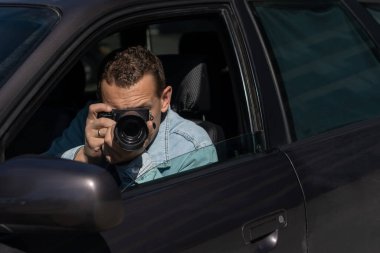 Paparazziler ya da güneş gözlüklü adamlar onun arabasında oturur ve ünlü birinin fotoğraflarını çeker. Arabada kamera olan bir casus. Özel dedektif ya da paparazzi gazeteci arabada oturuyor, kamerayla fotoğraf çekiyor..
